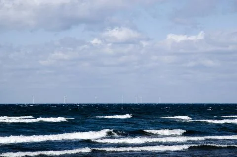 Waves with windmills in the horizon Stock Photos