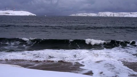 Waves on the winter cold shore of the Barents Sea during the polar night. Stock Photos