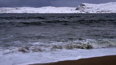 Waves on the winter cold shore of the Barents Sea during the polar night. Stock Photos
