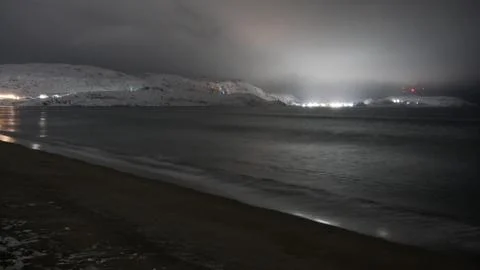 Waves on the winter cold shore of the Barents Sea during the polar night. Stock Photos