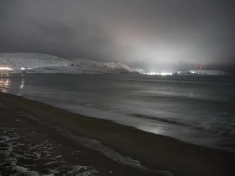 Waves on the winter cold shore of the Barents Sea during the polar night. Stock Photos
