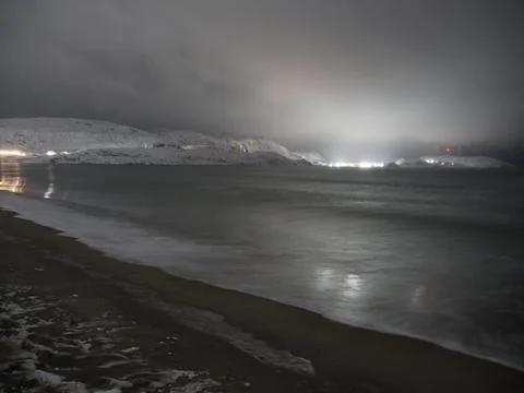 Waves on the winter cold shore of the Barents Sea during the polar night. Stock Photos