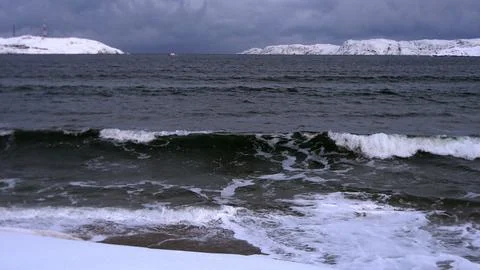Waves on the winter cold shore of the Barents Sea during the polar night. Stock Photos