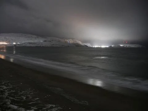 Waves on the winter cold shore of the Barents Sea during the polar night. Stock Photos