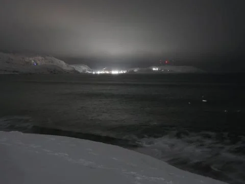 Waves on the winter cold shore of the Barents Sea during the polar night. Stock Photos