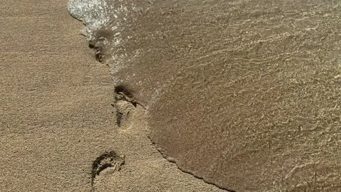 Waves wiping footprints on a sandy beach Stock Footage 295951257