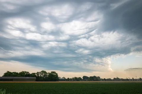Waving cloud forms over a rural landscape Stock Photos