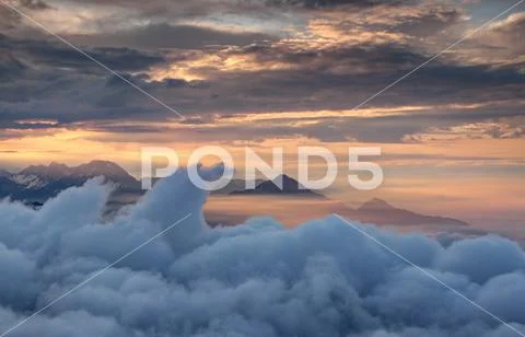 Waving clouds and jagged mountains in red glowing autumn mist Stock Photos