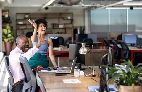 Waving at computer screen, diverse colleagues on video call in office Stock Photos