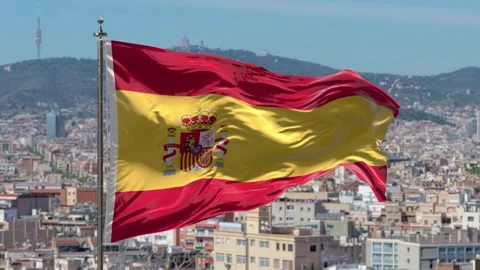 Waving flag of Spain on a flagpole above city skyline in daylight Stock Footage 329032176