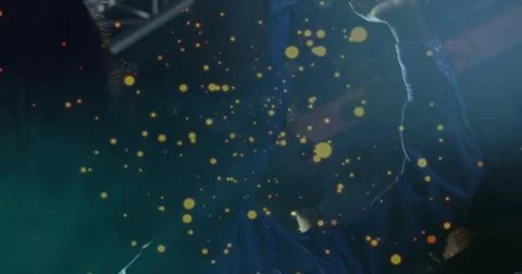 Waving man in blue jacket reaching upward at concert stage, with golden bokeh Stock Photos