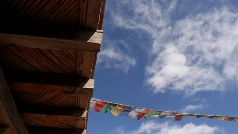 Waving prayer flags on the rooftop of a house with a blue sky in background 스톡 동영상 121963436