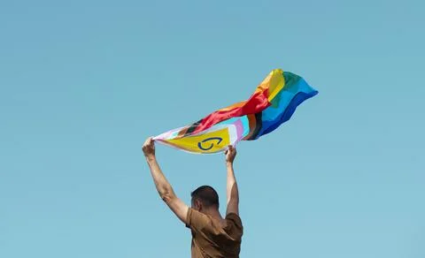 Waving a progress pride flag above his head Stock Photos