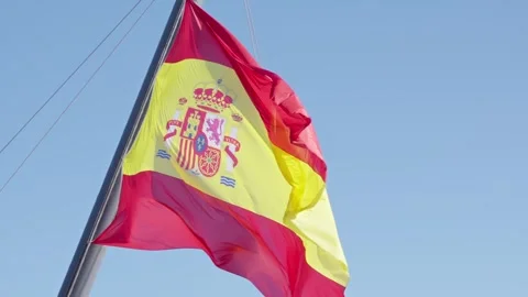 Waving Spanish flag under a clear blue sky Stock Footage 308811893