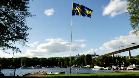 Waving Swedish flag in front of bridge and water 1029 Vidéo 50342606