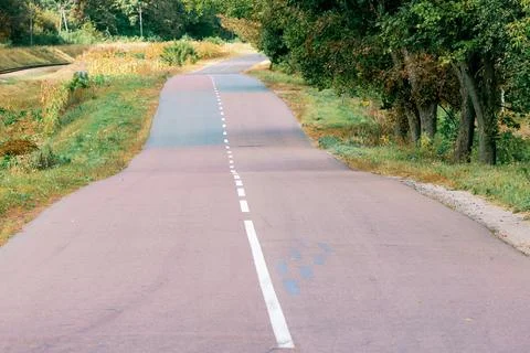 Wavy and bumpy asphalt road. Ahead is a long road that curves undulatingly in Stock Photos