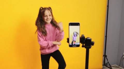 Wavy haired kid filming dance for online channel in studio using mobile phone on Stockbeeldmateriaal 287694285