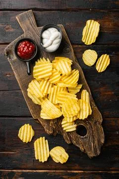 Wavy Potato Chips on old dark wooden table background, top view flat lay Foto stock