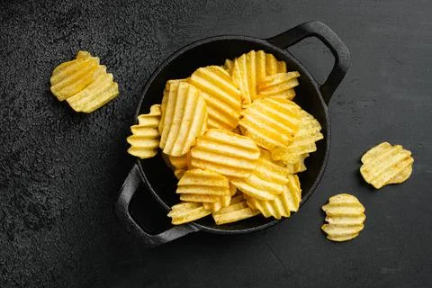 Wavy Ranch Flavored Potato Chips on black dark stone table background, top view Stock Photos