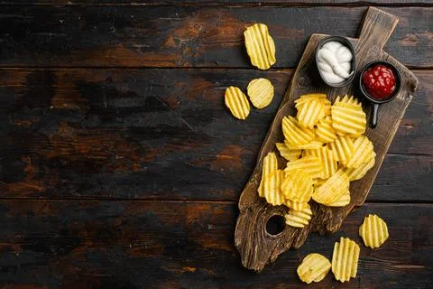 Wavy Reduced Fat chip on old dark wooden table background, top view flat lay Stock Photos