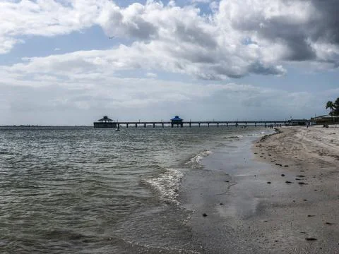 Wavy seashore with a dock in the background Stock Photos
