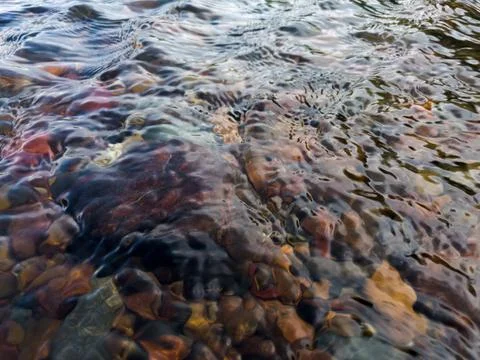 Wavy surface of  shallow rapid stream with colorful gravel at bottom Stock Photos