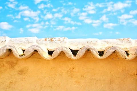 Wavy tiles above an adobe wall with bright blue sky Stock Photos