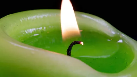Wax of a burning candle liquefies in fast motion while the camera rotates Stock Footage