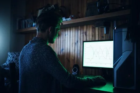 We all know geeks run the world. a young man using a computer and hacking in a Stock Photos