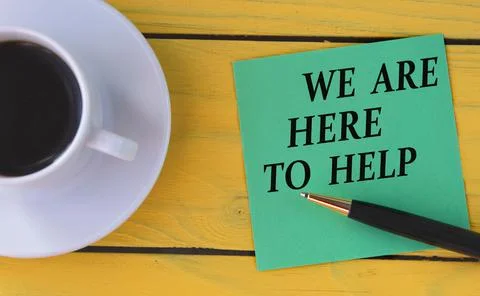 WE ARE HERE TO HELP - words on a green sheet on a yellow wooden background .. Stock Photos