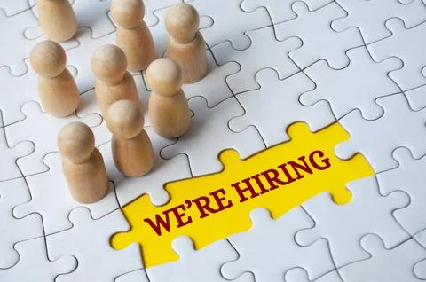 We are hiring text on missing jigsaw puzzle with wooden dolls.. Hiring and .. Stock Photos
