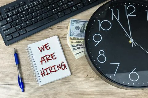 We are hiring written on a notebook with a computer keyboard clock and money Foto stock