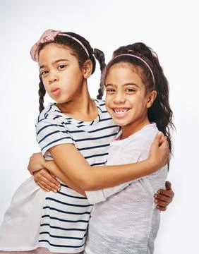 We are inseparable. two young girls embracing each other against a white Stock Photos