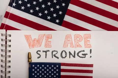 We are strong message hand written in note book with American flags Stock Photos