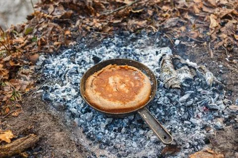 We bake bread from the dough in a pan on the coals of the fire Stock Photos