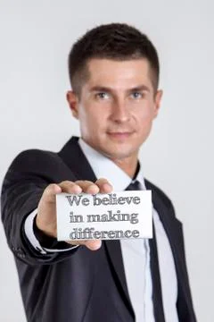 We believe in making difference - Young businessman holding a white card wi.. 写真素材