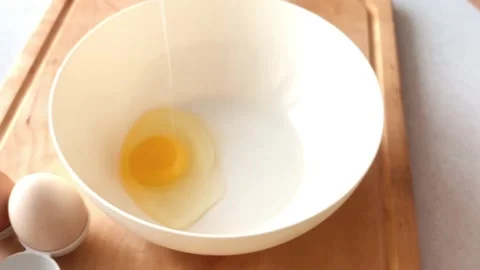 We break three eggs into a white bowl Stock Footage 225045612