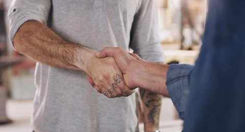 We can pull this off if we work together. two men shaking hands in a workshop. Stock Photos