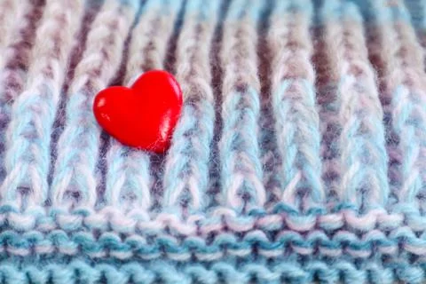We do our favorite needlework: a red heart on a knitted fabric, close-up Stock Photos