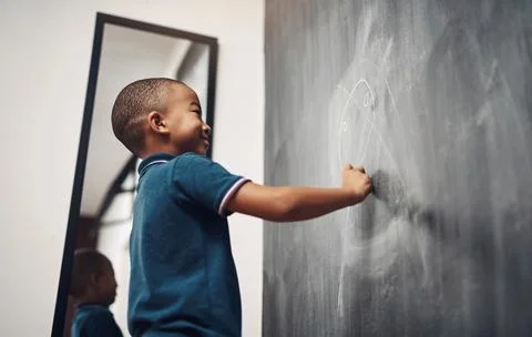 We express ourselves through visual art. a young boy writing on a blackboard at Stock-Fotos