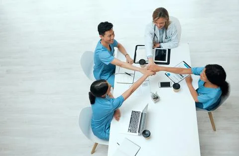 We have a plan of action. High angle shot of a group of doctors stacking their 写真素材