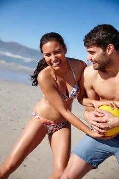 We keep each other on our toes. a happy couple playing with a ball together on a Stock Photos