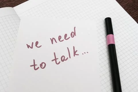 We need to talk message frase written on white piece of paper with a marker Stock Photos