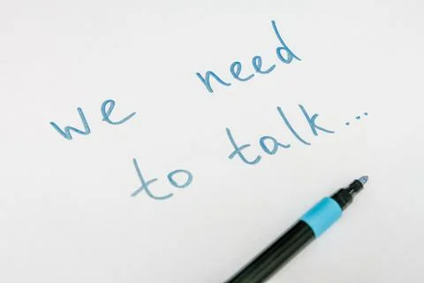 We need to talk message frase written on white piece of paper with a marker Stock Photos