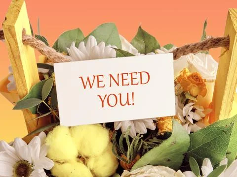 WE NEED YOU Message written on a business card placed in a basket with bloomi Stock Photos