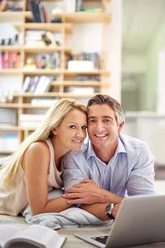 We share the same interests. Portrait of a mature couple lying on their living Foto stock