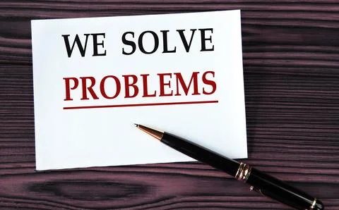 WE SOLVE PROBLEMS - words on a white sheet on a brown wooden background wit.. 写真素材