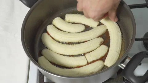 We spread the sliced bananas in a hot pan with melted caramel syrup and butter Stock Footage 232407963