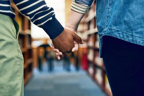 We study better when were together. a couple holding hands as they walk through 스톡 사진