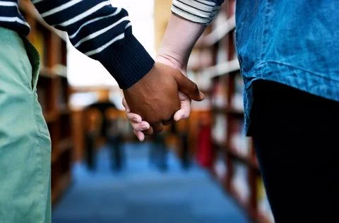 We study better when were together. a couple holding hands as they walk through 스톡 사진